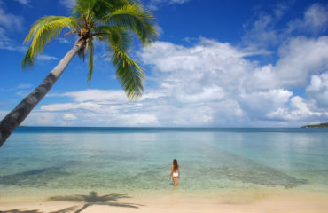 Young woman in bikini standing in clear water, Nananu-i-Ra islan