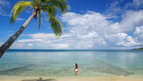 Young woman in bikini standing in clear water, Nananu-i-Ra islan